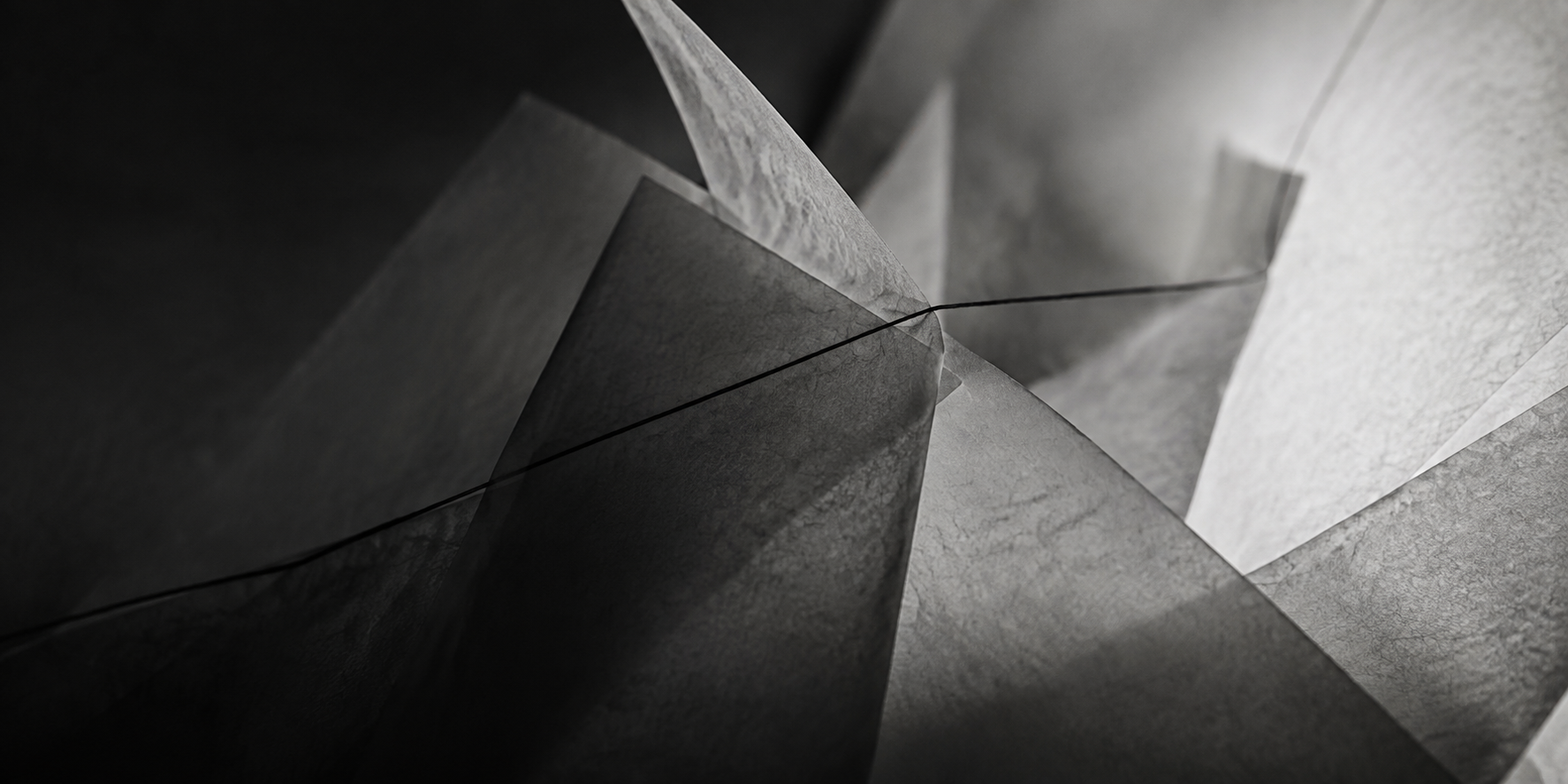 Overlapping translucent paper sheets crossed by a fine dark line.
